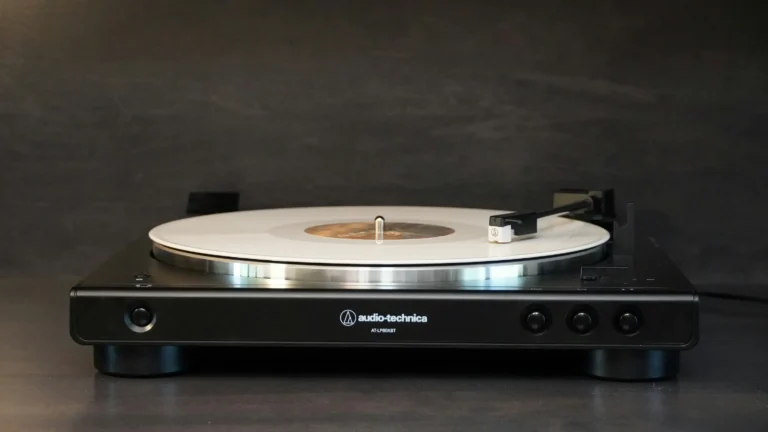 Platine vinyle Audio-Technica AT-LP60XBT noire à courroie en vue de face avec disque vinyle blanc en lecture, ambiance sombre
