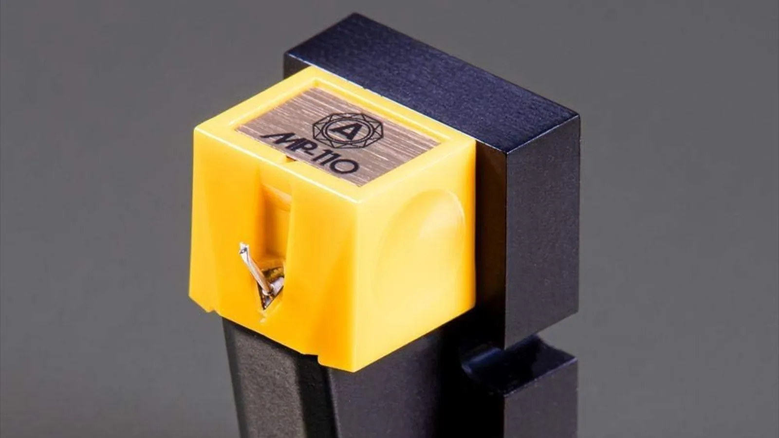 Détail de la cellule Nagaoka MP-110, corps jaune avec étiquette MP-110 dorée et stylet elliptique en avant-plan