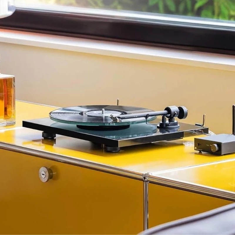 Pro-Ject T1 EVO BT noire en situation d'écoute sur meuble jaune avec préampli phono à proximité — illustration usage hi-fi compact