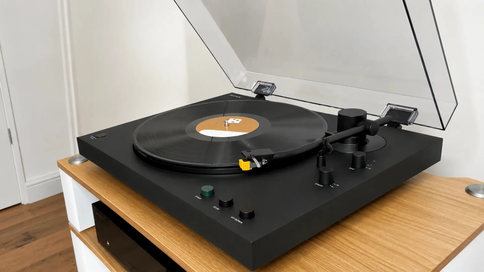 Platine vinyle Sony PS-LX5BT noire, capot anti-poussière ouvert, posée sur un meuble bois